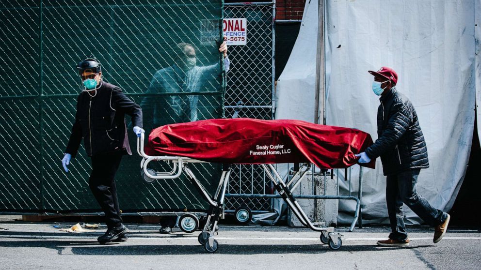 PHOTO: Hospital employees and funeral service employees transfer a body from a temporary mobile morgue into a funeral home vehicle outside of the Brooklyn Hospital Center, in Brooklyn, New York, April 8, 2020.