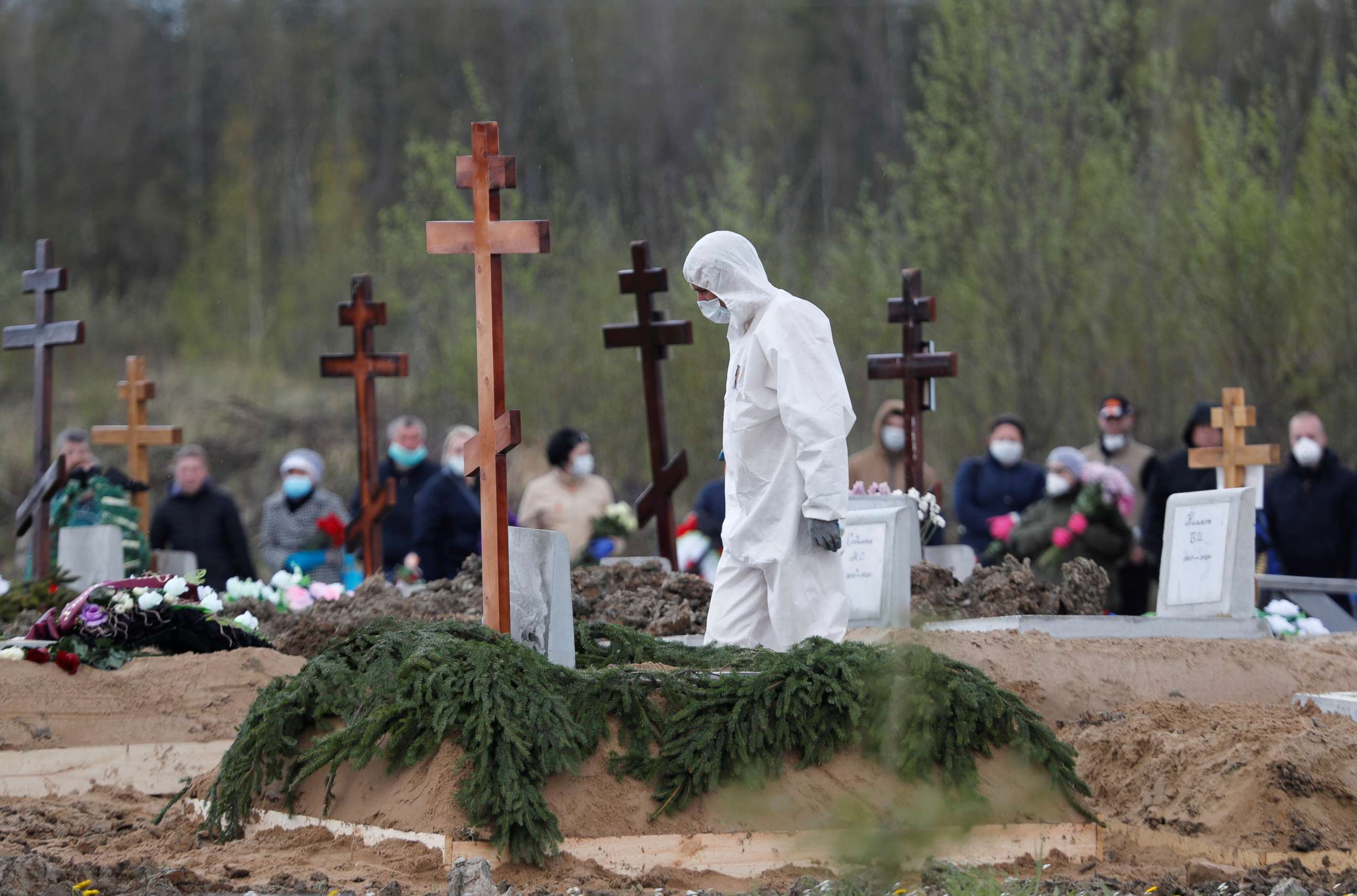 PHOTO: A worker using personal protective equipment walks near a grave while burying a person in a special purpose section of a graveyard on the outskirts of Saint Petersburg, Russia, May 13, 2020.