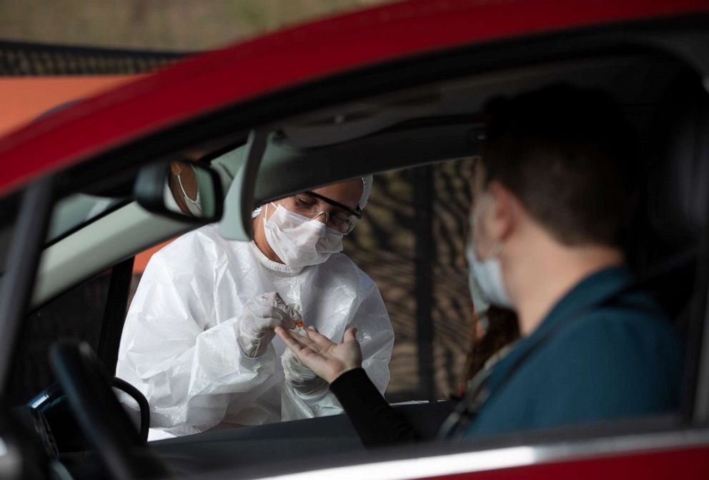 PHOTO: A health worker collects a sample from a person at a drive-thru testing site for COVID-19 in Niteroi, Brazil, on June 3, 2020, amid the coronavirus pandemic.