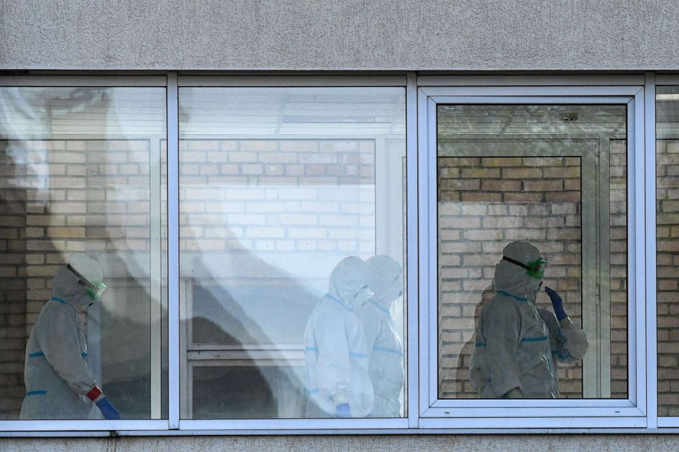 PHOTO: Health workers wearing protective equipment walk behind glass windows inside a hospital where patients infected with the novel coronavirus are being treated in Khimki, outside Moscow, Russia, on May 3, 2020.