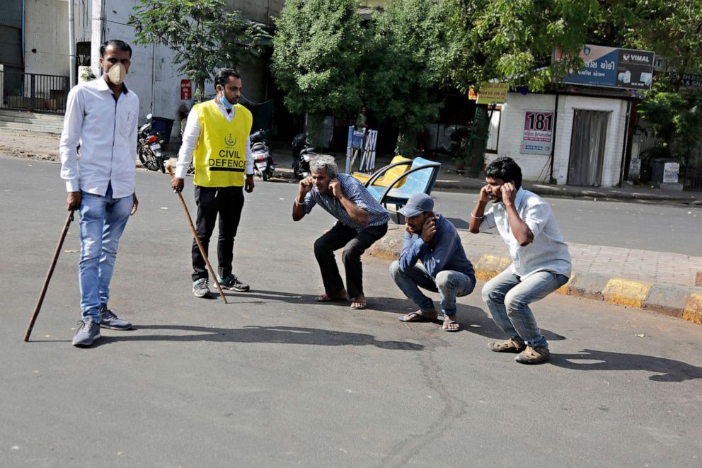 PHOTO: An Indian policeman, left, and a civil defense person, 2nd left, make three men perform sit ups while holding their ear lobes, as a punishment for stepping out without a valid reason during a lockdown in Ahmedabad, India, March 24, 2020.