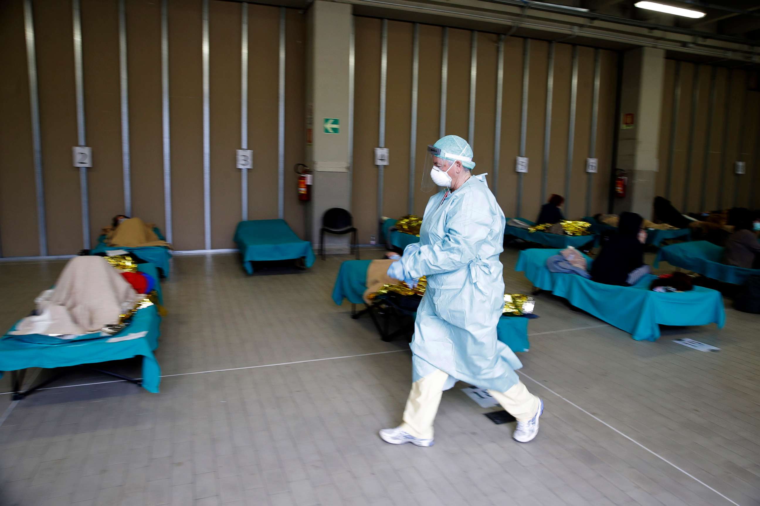 PHOTO: Patients lie on beds as a doctor walks past them, at a one of the emergency structures that were set up to ease procedures at the Brescia hospital, northern Italy, March 12, 2020. 