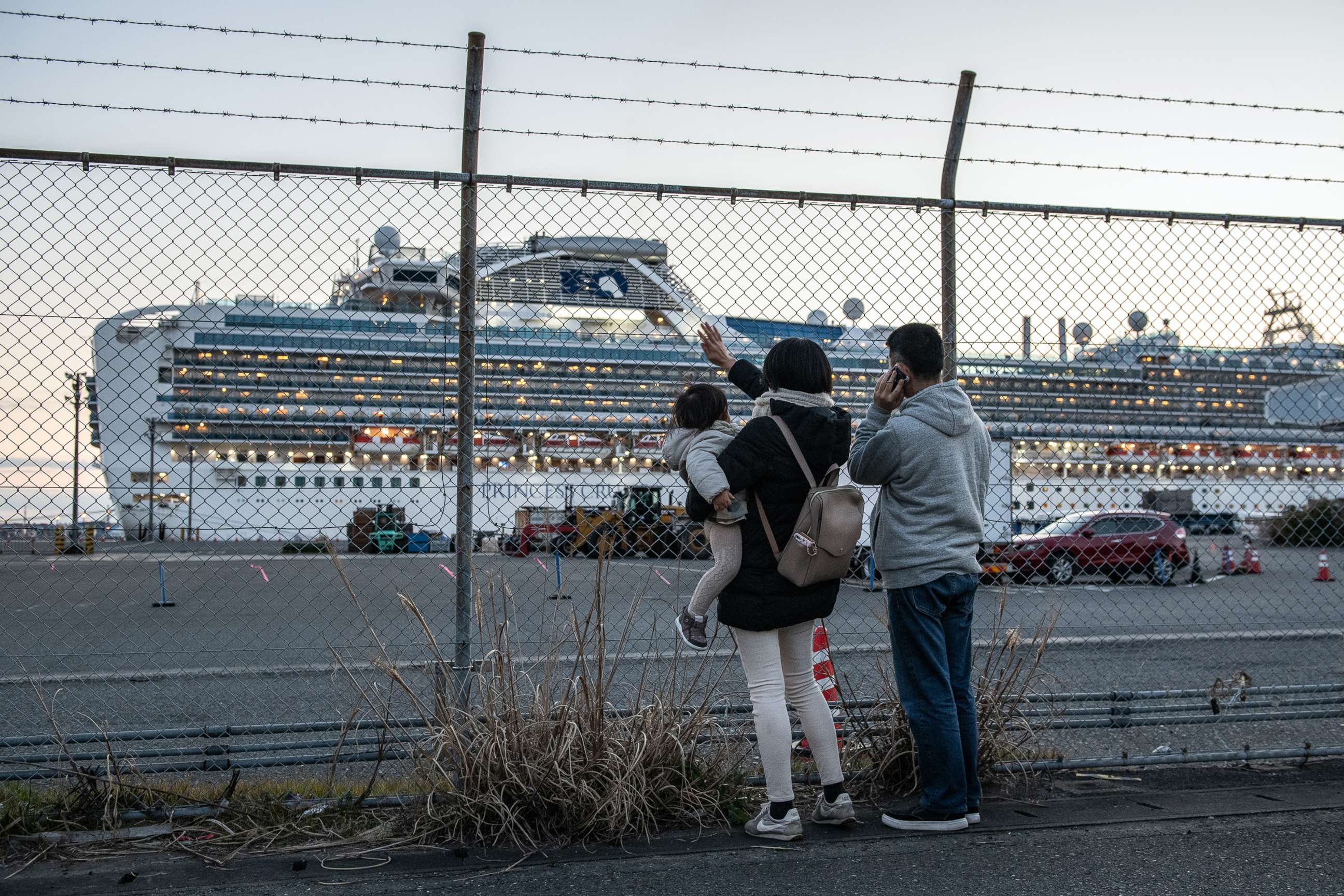 PHOTO: People wave to family on board the Diamond Princess cruise ship as it sits docked at Daikoku Pier where it is being resupplied and newly diagnosed coronavirus cases taken for treatment as it remains in quarantine, Feb. 11, 2020, in Yokohama, Japan.