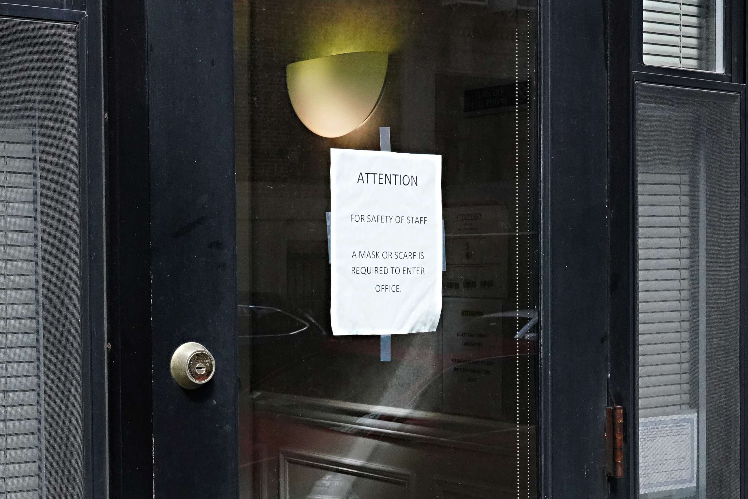 PHOTO: A sign posted on a door reads 'for safety of staff a mask or scarf is required to enter office' on April 15, 2020, in New York City.