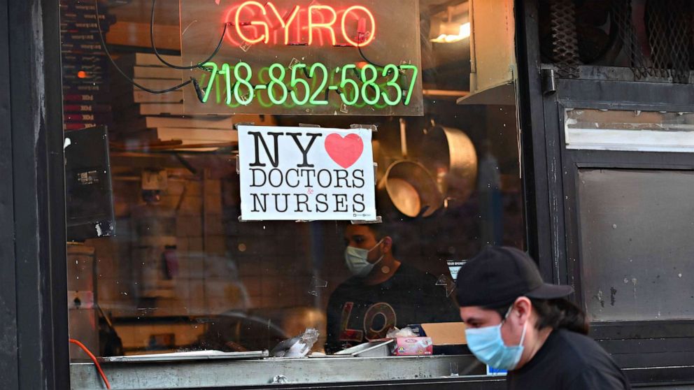 PHOTO: A man wearing a face mask walks by a pizzeria near the Brooklyn Hospital Center with a sign of support for doctors and nurses, on April 15, 2020, in New York City, amid the novel coronavirus outbreak.