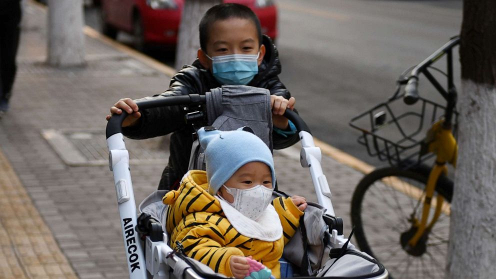 PHOTO: A boy wears a mask as a preventive measure against the COVID-19 coronavirus as as he pushes another child in a pram in Beijing, March 9, 2020.
