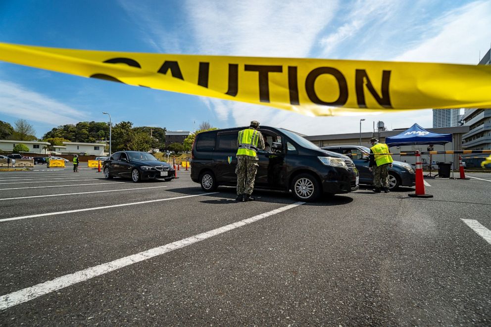 PHOTO: In this image released by the U.S. Department of Defense, Commander Fleet Activities Yokosuka's security department sailors direct incoming gate traffic to COVID-19 screening stations on base in Yokosuka, Japan, on April 10, 2020.