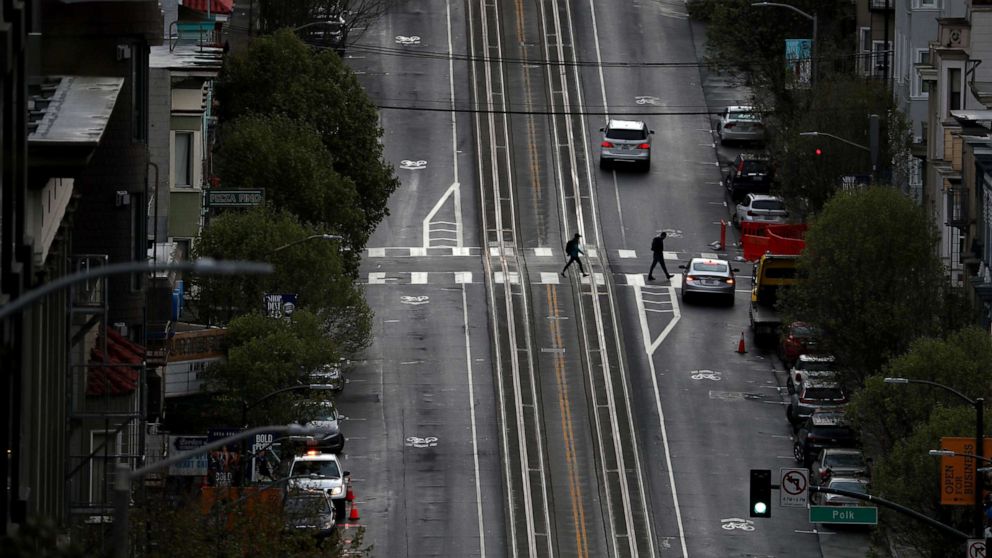 PHOTO: Two pedestrians cross an empty street, on March 16, 2020 in San Francisco.