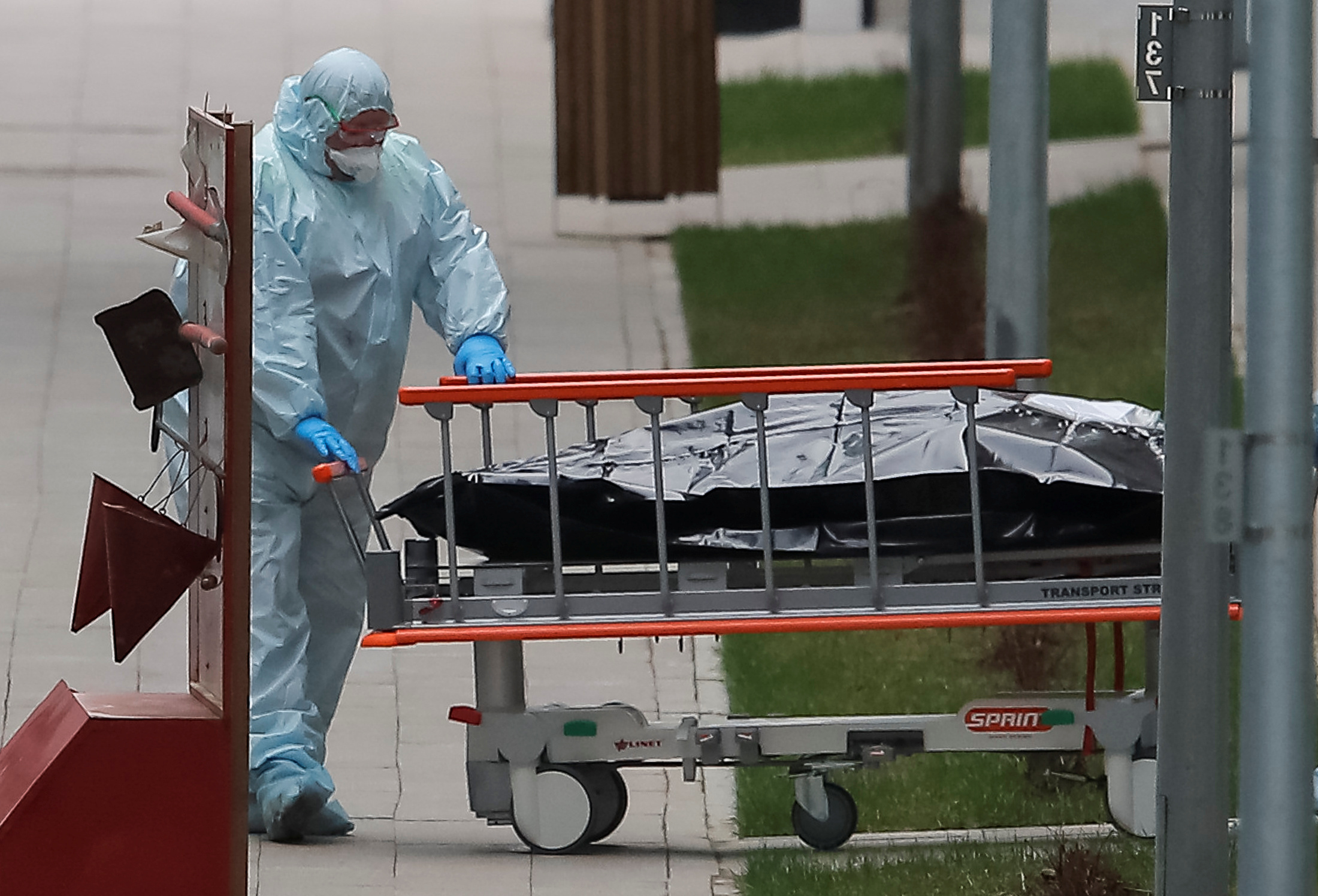 PHOTO: A medical specialist wearing protective gear pulls a stretcher toward an ambulance while relocating a bag, which presumably contains a human body, outside a hospital for patients infected with coronavirus on the outskirts of Moscow, April 20, 2020.