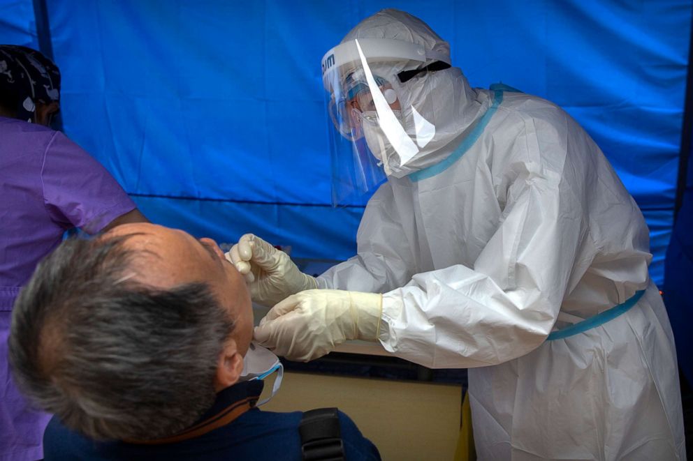 PHOTO: A worker wearing a protective suit swabs a man's throat for a COVID-19 test at a community health clinic in Beijing, China, on June 28, 2020.