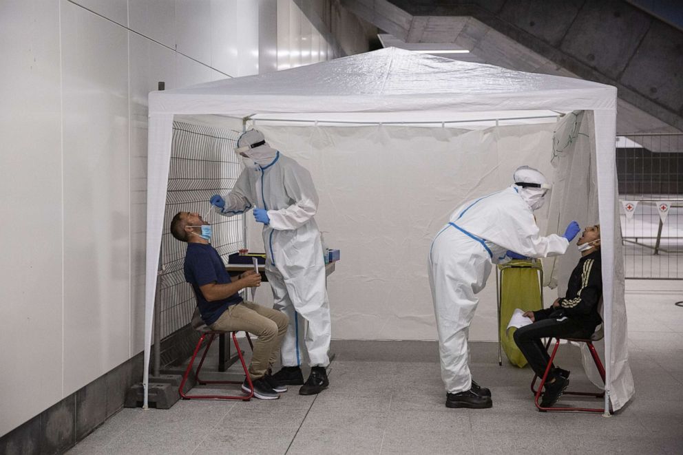 PHOTO: Members of the German Red Cross wear protective suits while taking throat swab samples at a COVID-19 testing station set up at the main railway station in Berlin, Germany, on Aug. 18, 2020.