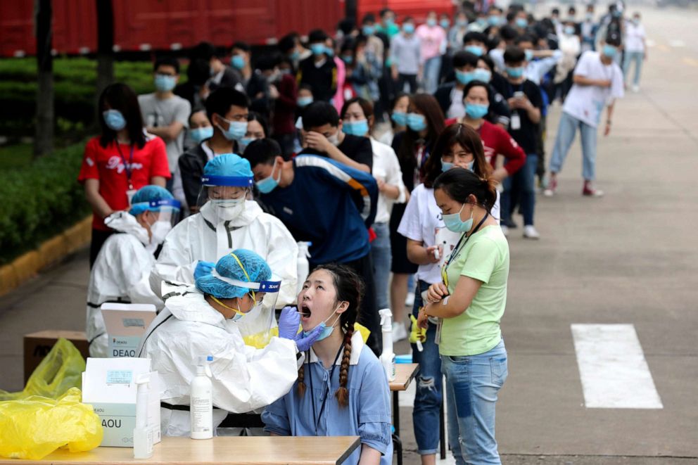 PHOTO: People line up for medical workers to take swabs to test for COVID-19 at a large factory in Wuhan in central China's Hubei province on May 15, 2020.
