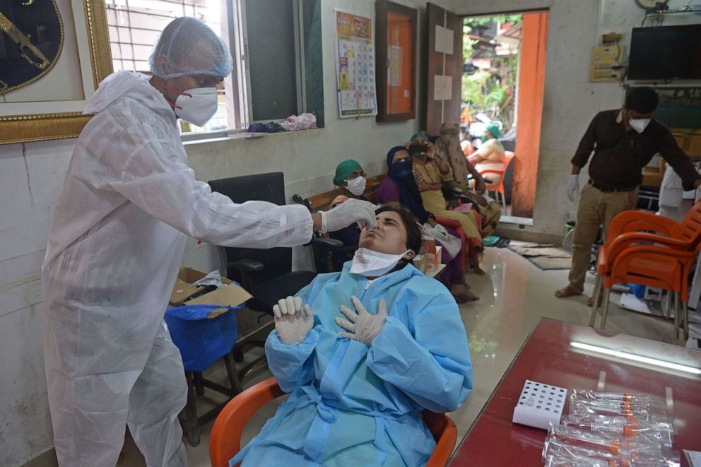 PHOTO: A health worker wearing personal protective equipment collects a swab sample from a doctor, who was on duty at a screening camp for residents, to test for COVID-19 in Mumbai, India, on Aug. 17, 2020.