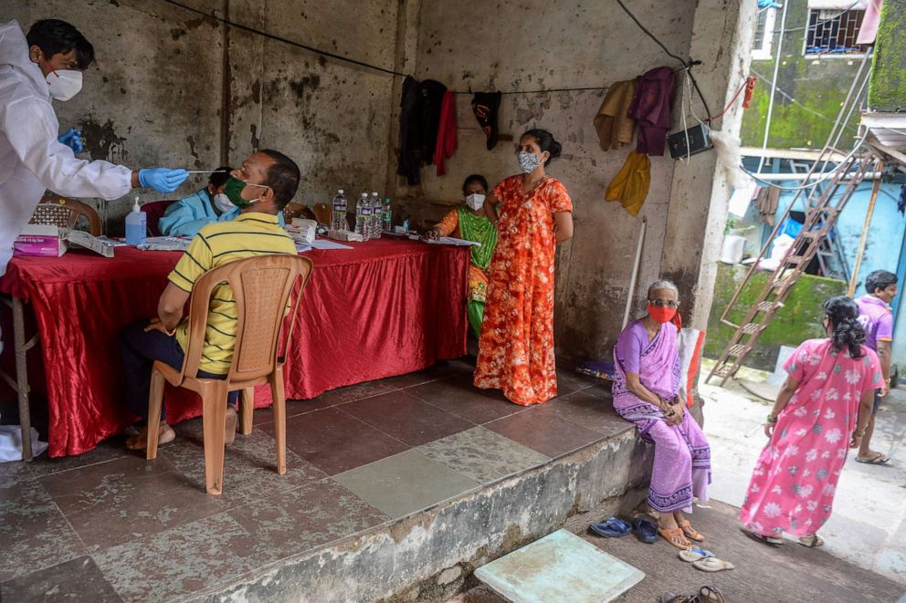 PHOTO: A health worker (left) wearing personal protective equipment collects a nasal swab from a resident during a COVID-19 screening in Mumbai, India, on Aug. 19, 2020.