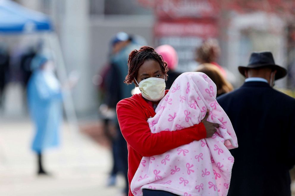 PHOTO: A woman holds a child at a testing site for COVID-19 outside Roseland Community Hospital in Chicago, April 7, 2020.