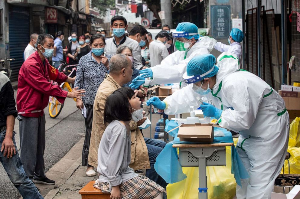 PHOTO: This file photo taken on May 15, 2020, shows medical workers taking swab samples from residents to be tested for COVID-19 in a street in Wuhan in China's central Hubei province.