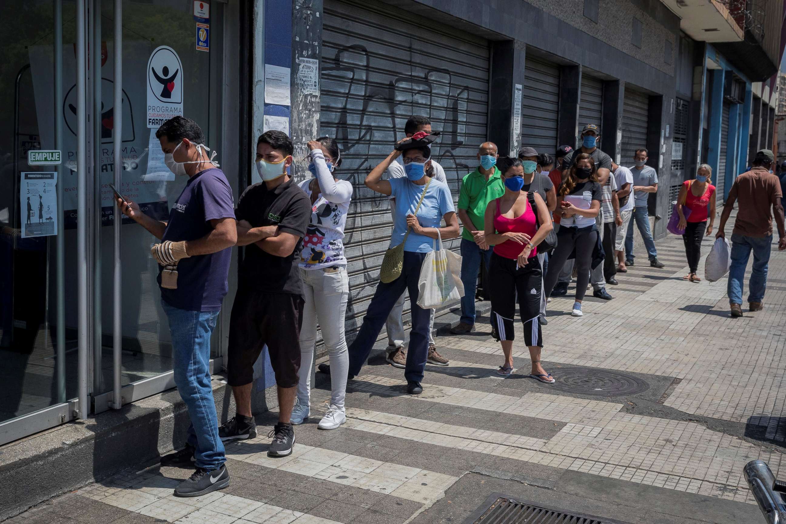 PHOTO: Dozens of people stand in a long line to stock up on medications and personal hygiene products at a pharmacy in Caracas, Venezuela, March 25, 2020.