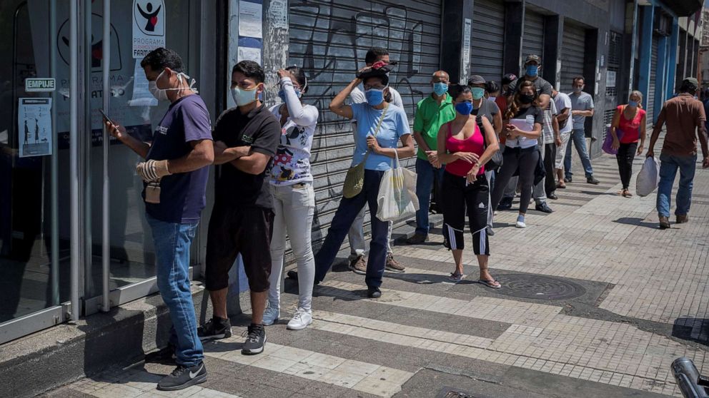 PHOTO: Dozens of people stand in a long line to stock up on medications and personal hygiene products at a pharmacy in Caracas, Venezuela, March 25, 2020.