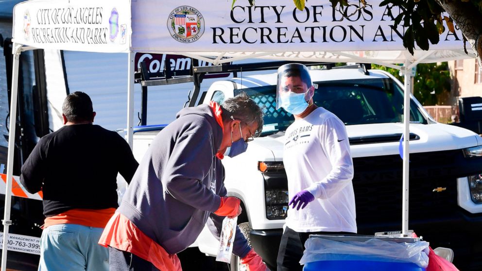 PHOTO: A coronavirus test site worker wearing a face shield and mask watches over the situation as people drop off their Covid-19 test at a mobile pop-up test site in Los Angeles,  Dec. 3, 2020. 