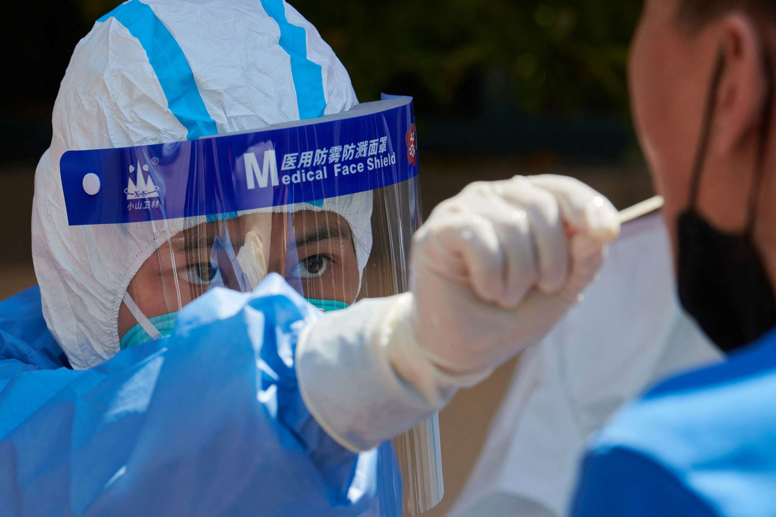 PHOTO: A health worker wearing personal protective equipment conducts a swab test for the COVID-19 coronavirus in Shanghai, April 17, 2022.