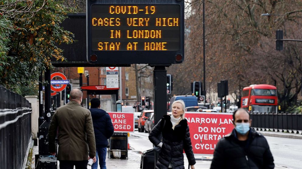 PHOTO: Pedestrians walk past a sign alerting people about high numbers of COVID-19 cases in central London on Dec. 23, 2020.