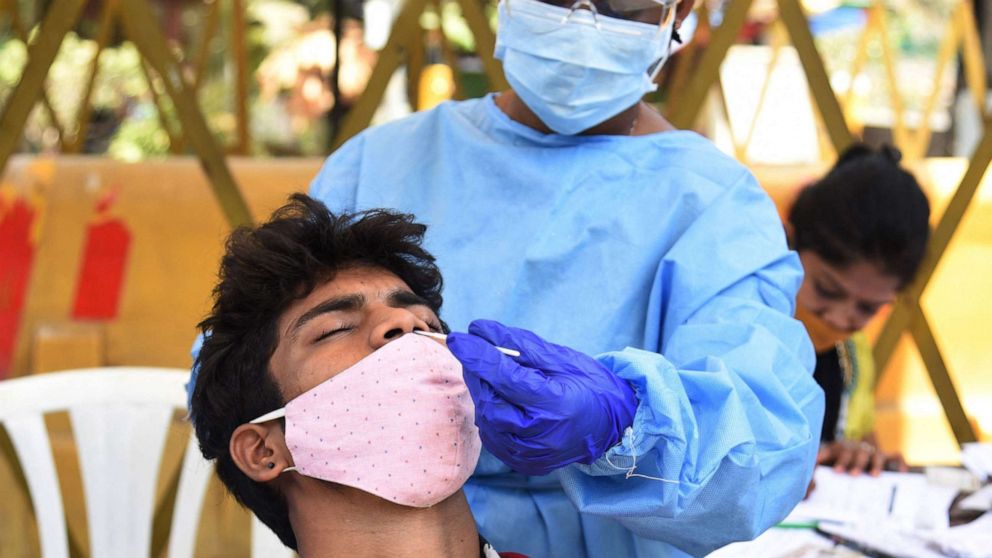 PHOTO: A health worker takes a swab sample from a man during compulsory COVID-19 testing for visitors at the Gateway of India in Mumbai in the Indian state of Maharashtra on April 3, 2021.