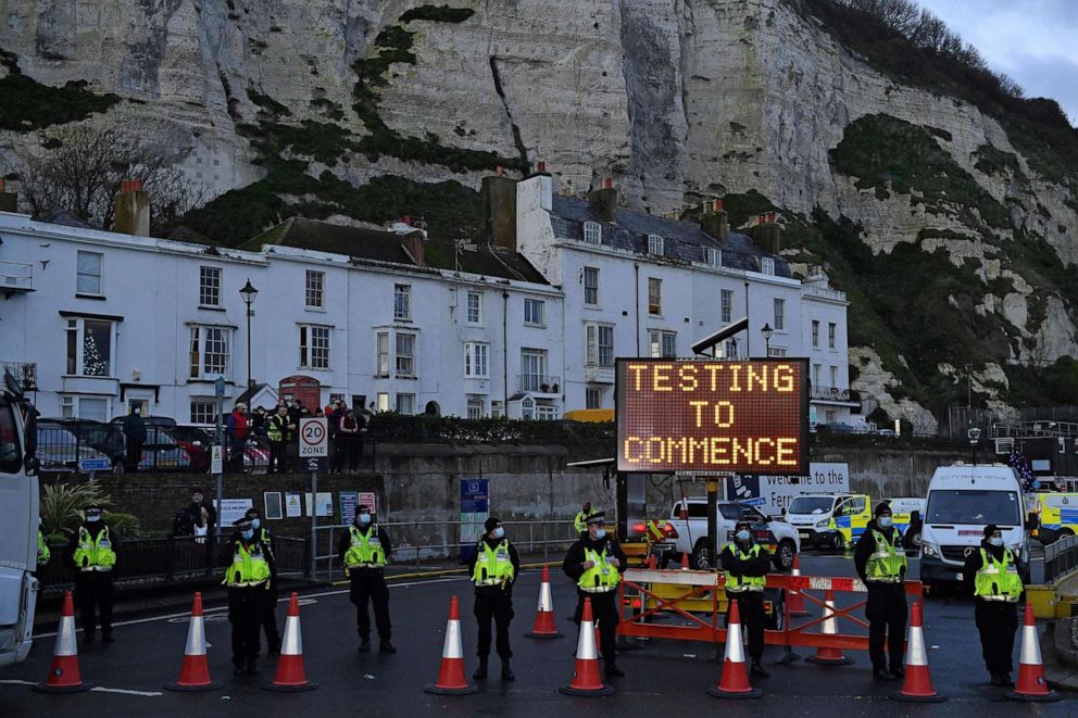 PHOTO: Police officers stand beneath a sign reading "Testing to Commence", at the entrance to the Port of Dover in Kent, south east England, on Dec. 23, 2020, where COVID-19 testing is set to begin on drivers who have been queueing to leave the UK.