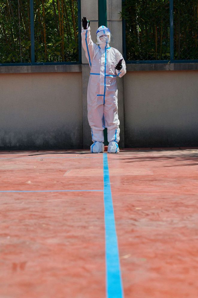 PHOTO: A community volunteer wearing personal protective equipment gestures during a test for the COVID-19 coronavirus in a compound during a lockdown in Pudong district in Shanghai, April 17, 2022.