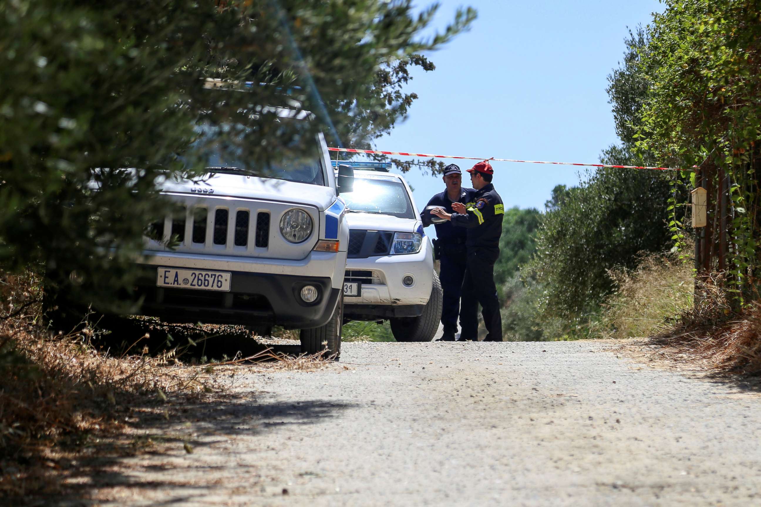 PHOTO: A police officer and a member of a fire brigade search and rescue team stand behind a police cordon, in an area where the body of a woman was found, near the village of Kolimpari on the island of Crete, Greece, July 9, 2019.