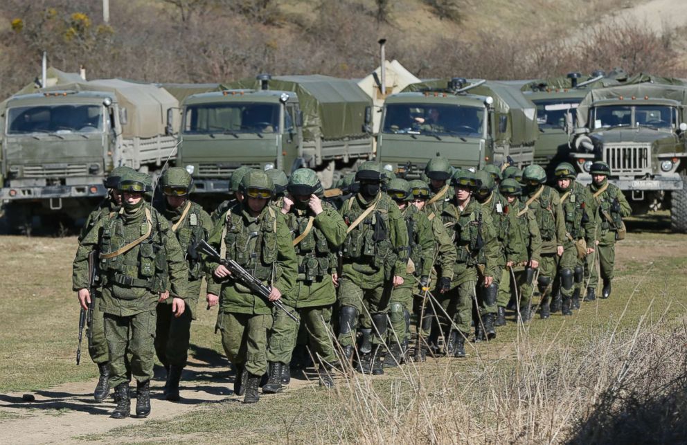 PHOTO: Military personnel, believed to be Russian servicemen, walk outside the territory of a Ukrainian military unit in the village of Perevalnoye outside Simferopol, in Crimea, March 3, 2014.