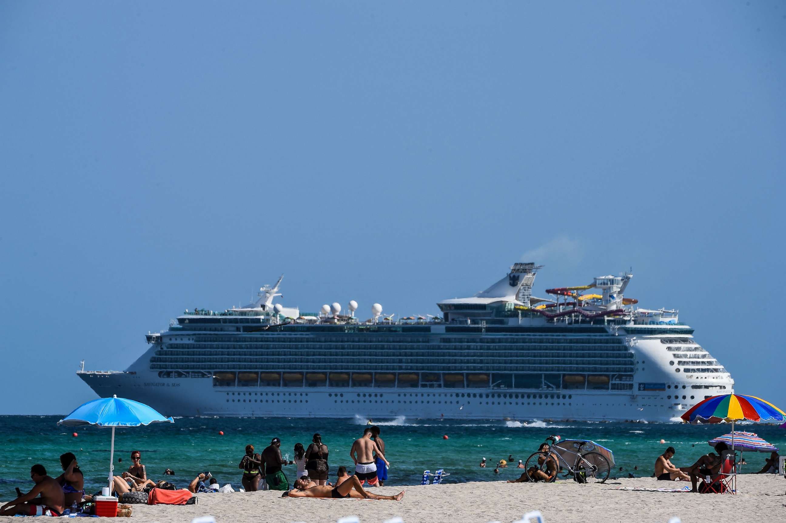 PHOTO: A cruise ship sails in the background as people relax in Miami Beach, Fla., on July 2, 2020.