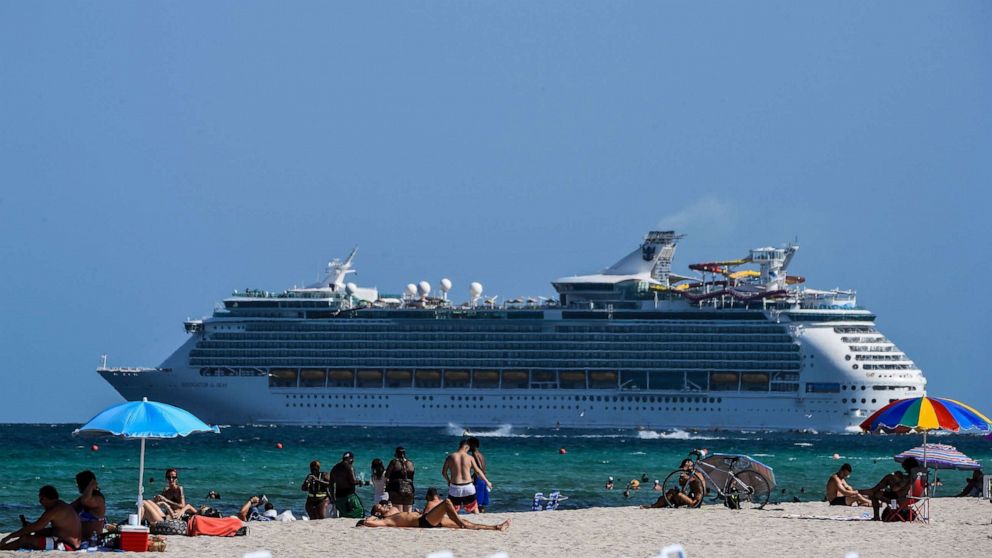 PHOTO: A cruise ship sails in the background as people relax in Miami Beach, Fla., on July 2, 2020.