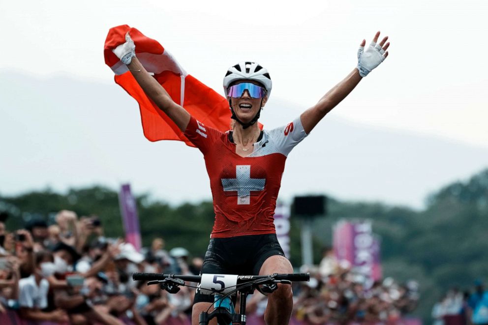 PHOTO: Jolanda Neff of Switzerland celebrates as she crosses the finish line for the gold medal during the women's cross-country mountain bike competition at the 2020 Summer Olympics, Tuesday, July 27, 2021, in Izu, Japan.