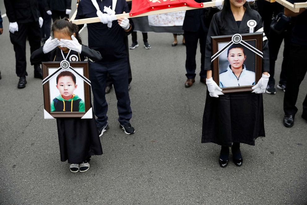 PHOTO: A girl and her North Korean defector mother hold portraits of a 42-year-old defector mother and  her 6-year-old son who were found dead in starvation as they march during their funeral in Seoul, South Korea, Sept. 21, 2019.