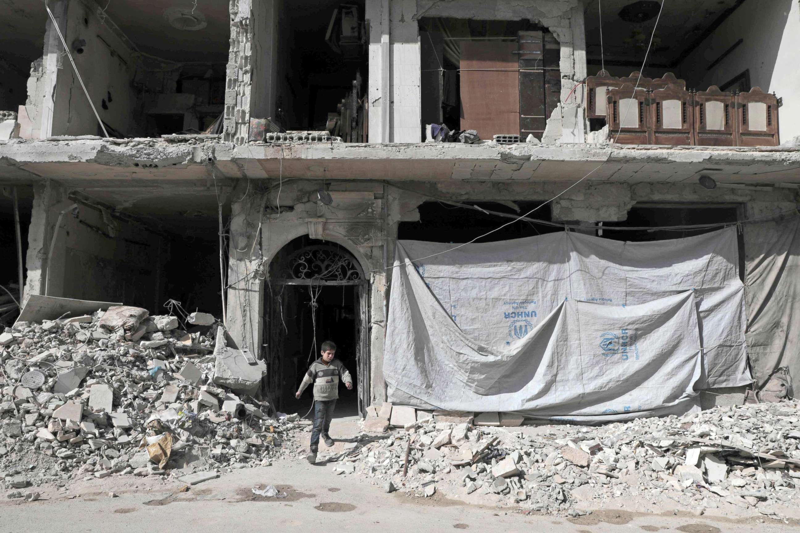 PHOTO: A Syrian child leaves a destroyed building, March 25, 2018, in Douma, in Eastern Ghouta on the outskirts of the capital Damascus.