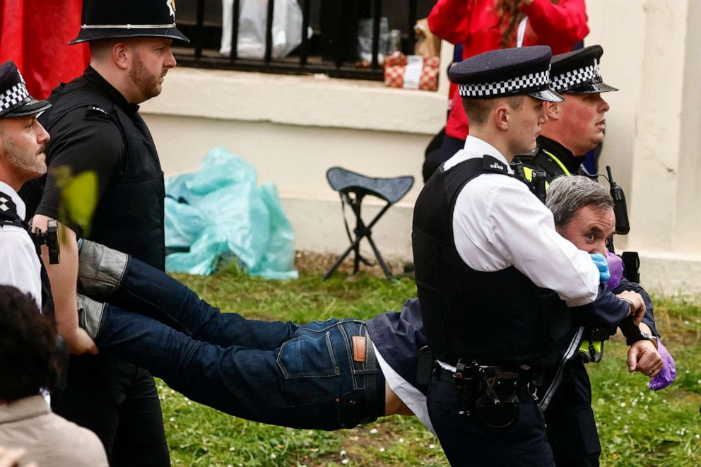 PHOTO: Police officers detain a member of "Just Stop Oil" movement as people gather to watch the procession during the Coronation of King Charles III and Queen Camilla, May 6, 2023 in London.