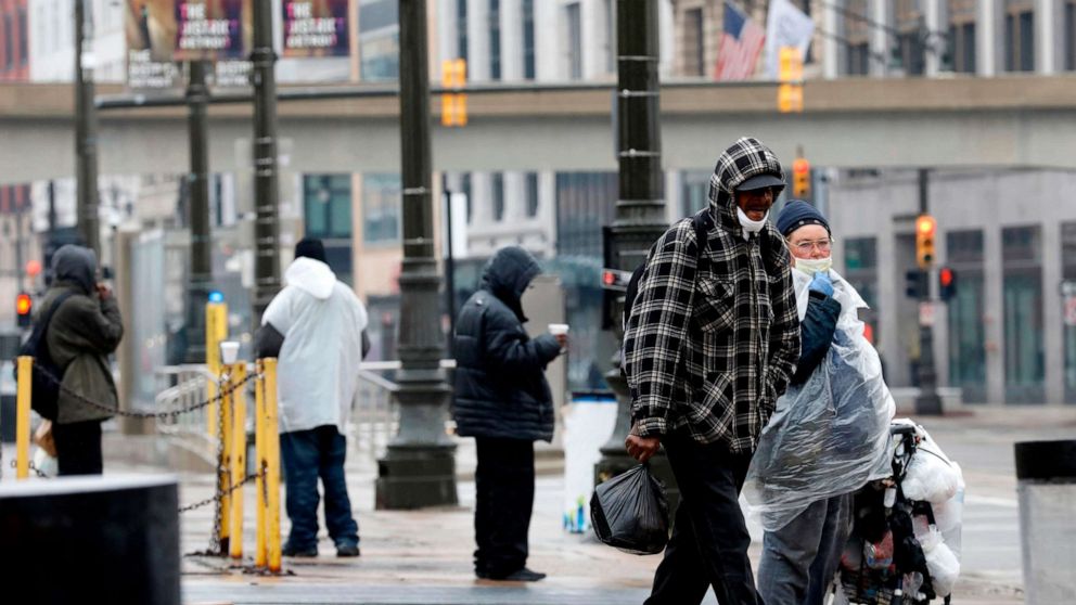 PHOTO: People wait for a bus as they wait on Woodward Avenue in Detroit, April 7, 2020.