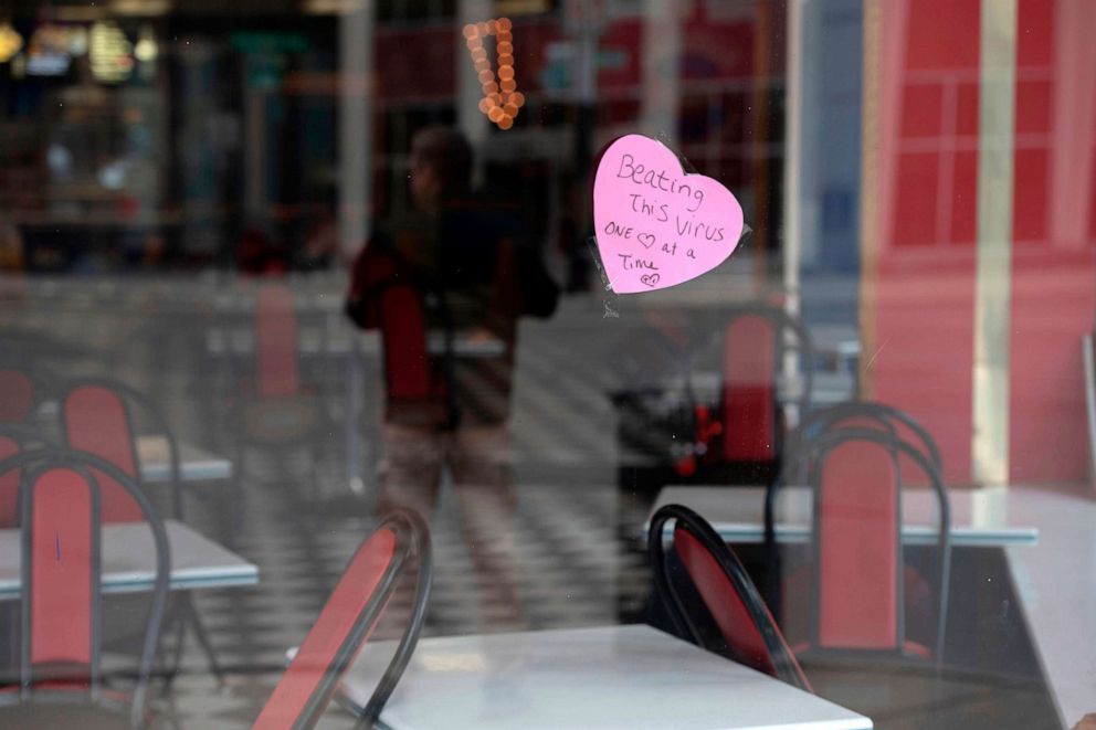 PHOTO: A sign hangs in the window of American Coney Island restaurant in Detroit, Michigan reading "Beating this virus one heart at a time," March 24, 2020, during the coronavirus pandemic.