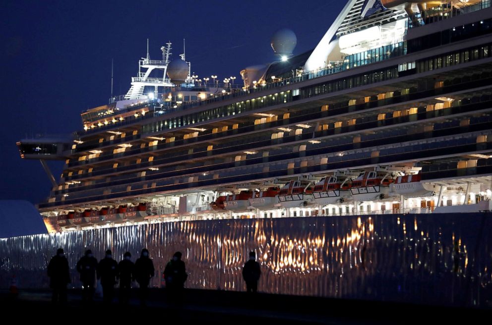 FILE PHOTO: Workers walk past the coronavirus-hit cruise ship Diamond Princess as they leave the Yokohama Port, south of Tokyo, Japan, on Feb. 21, 2020.