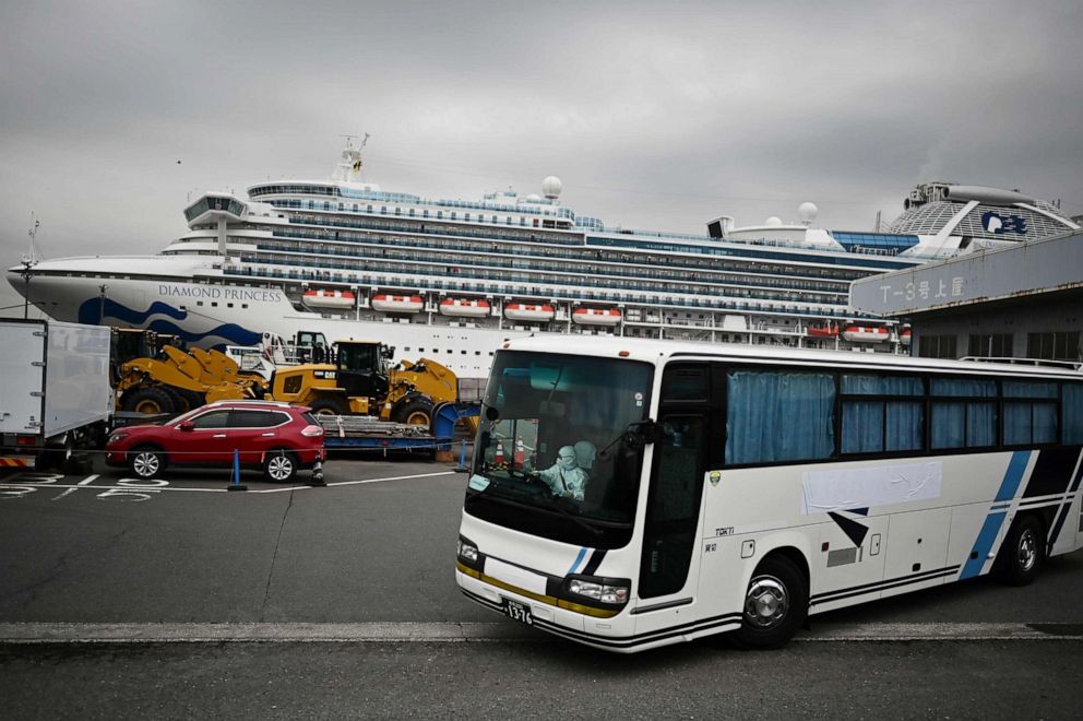 PHOTO: A bus with a driver wearing full protective gear departs from the dockside next to the Diamond Princess cruise ship, which has thousands of people quarantined on board due to fears of the new coronavirus, in Yokohama port, Japan, on Feb. 14, 2020.