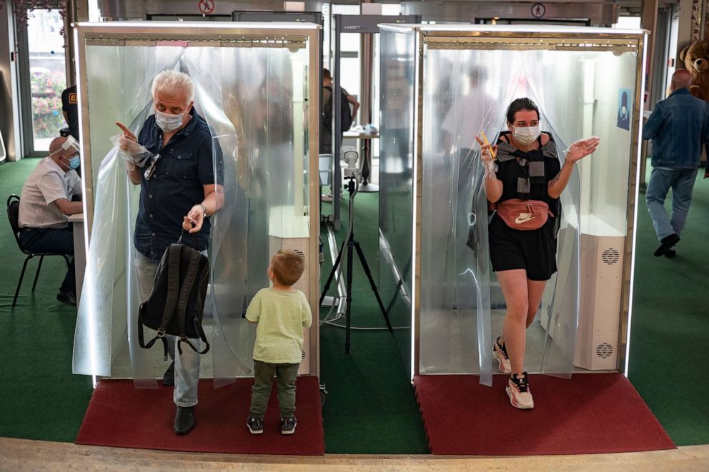 PHOTO: People wearing face masks and gloves to protect against the novel coronavirus come through passages equipped with disinfectant sprays at a shopping mall entrance in Moscow, Russia, on Aug. 3, 2020.