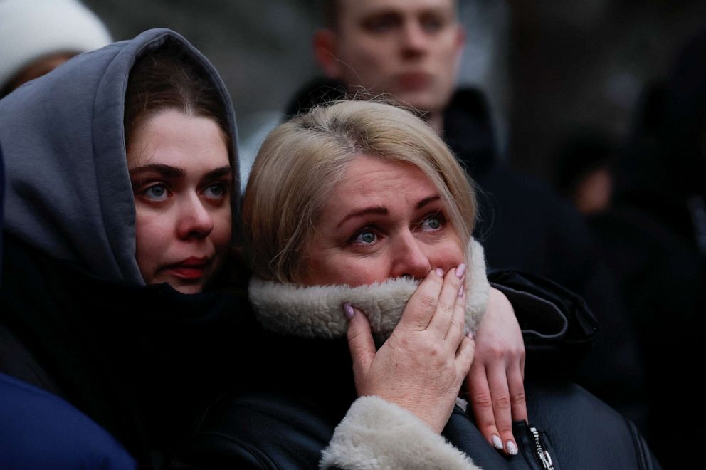 PHOTO: Women look on as emergency personnel work at the site where an apartment block was heavily damaged by a Russian missile strike in Dnipro, Ukraine, Jan. 15, 2023.
