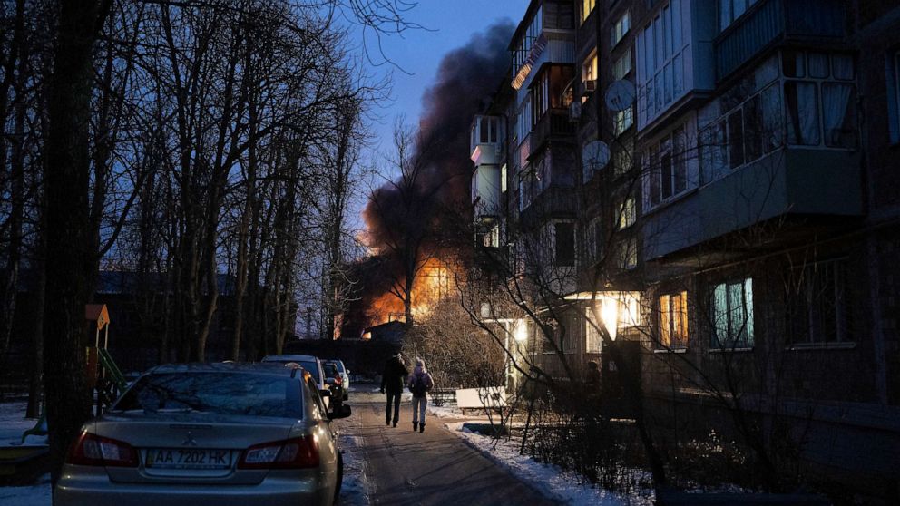 PHOTO: Residents watch at a burning infrastructure project hit during a Russian drone night strike in Kyiv, Ukraine, Dec. 19, 2022.