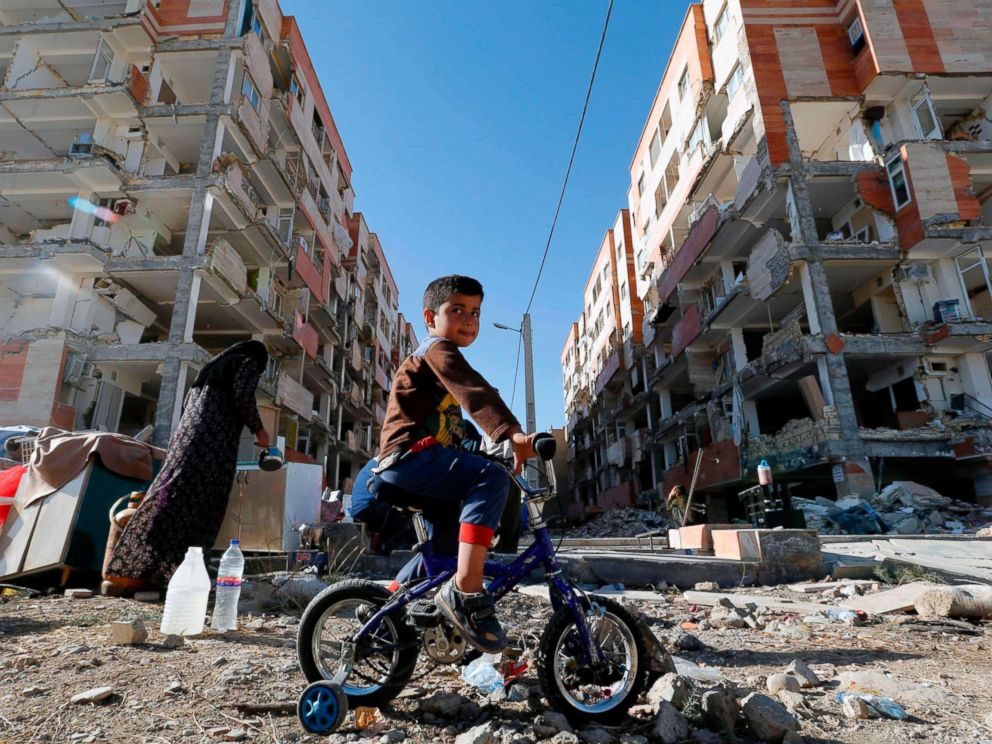 PHOTO: A boy rides a bicycle past earthquake damaged buildings in the town of Sarpol-e Zahab in Irans western Kermanshah province near the border with Iraq, Nov. 14, 2017. A powerful earthquake struck the region on Nov. 12.