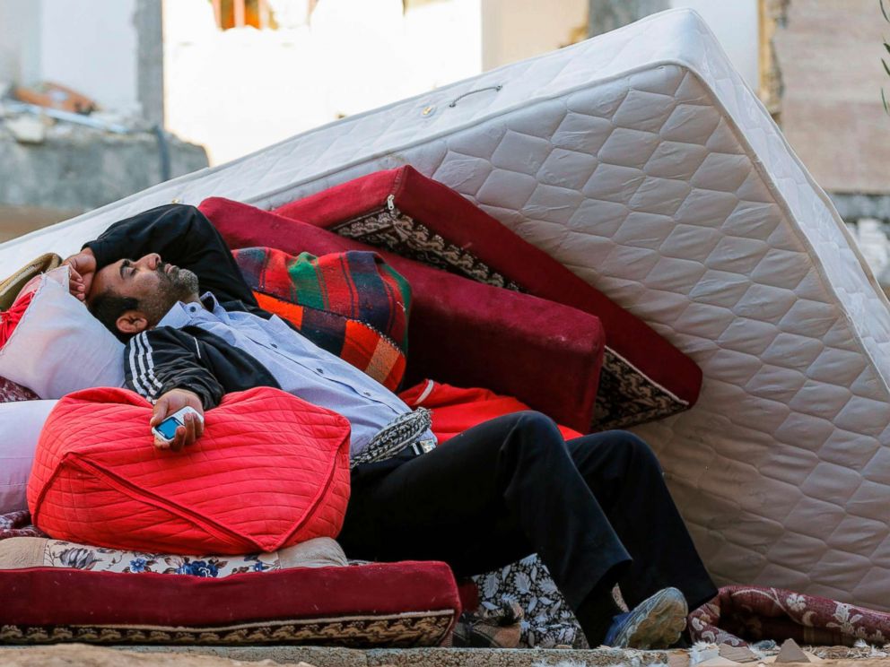 PHOTO: A man lies atop salvaged mattresses and other possessions outside damaged buildings in the town of Sarpol-e Zahab in the western Kermanshah province of Iran on Nov. 14, 2017, following a 7.3 magnitude earthquake two days before.