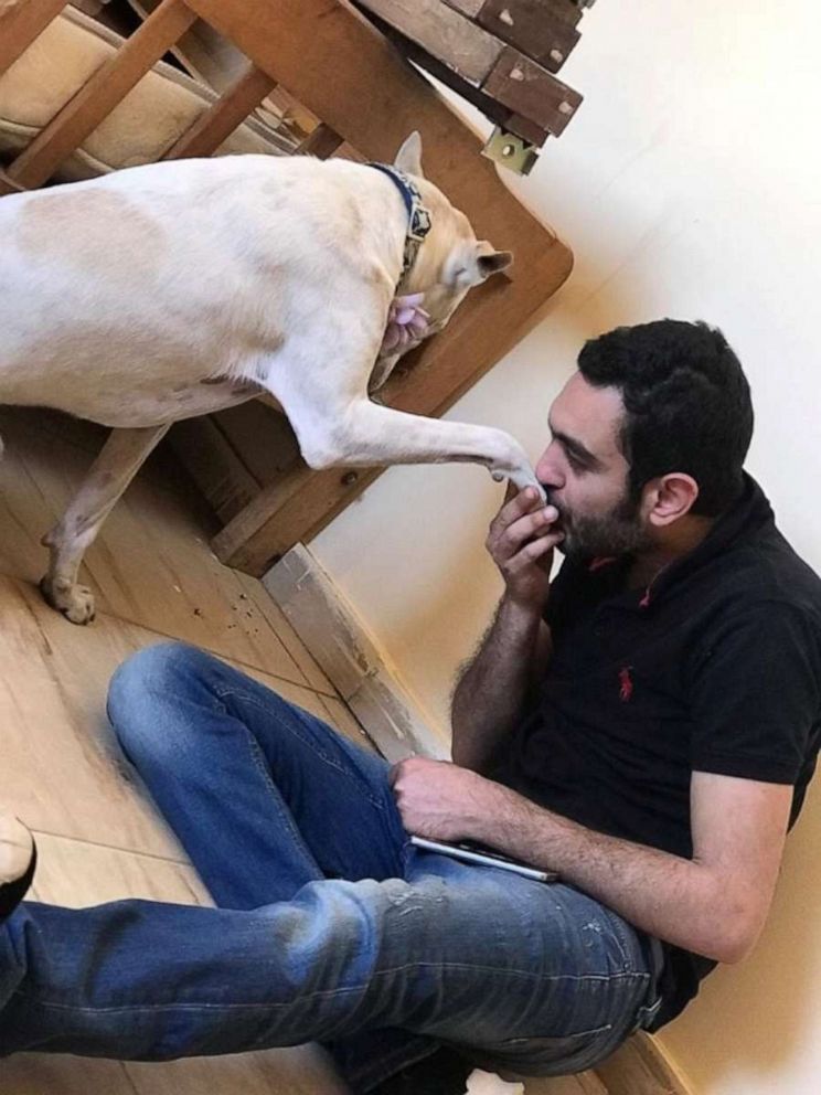 PHOTO: Ahmed Al Shurbaji kisses the hand of one of the "baladi" dogs at HOPE shelter, in Cairo.