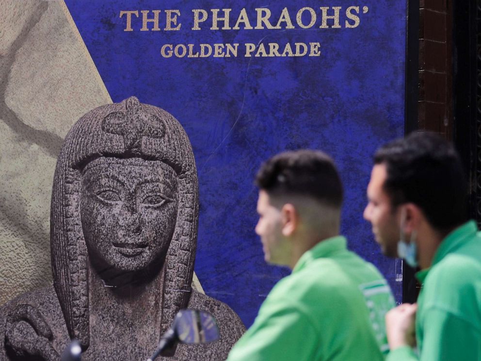 PHOTO: Men pass in front of a poster for The Pharaohs' Golden Parade in Cairo for the transfer of 22 mummies from the Egyptian Museum in Tahrir Square to the National Museum of Egyptian Civilization in Fustat, April 1, 2021.