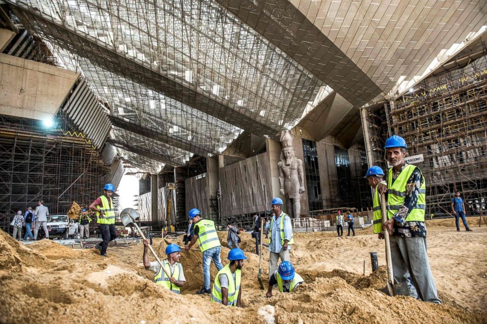 PHOTO: Egyptian construction workers excavate outside the entrance of the Grand Egyptian Museum in Giza during its construction June 10, 2018, with the 3,200-year-old colossal statue of King Ramses II seen in the background. 