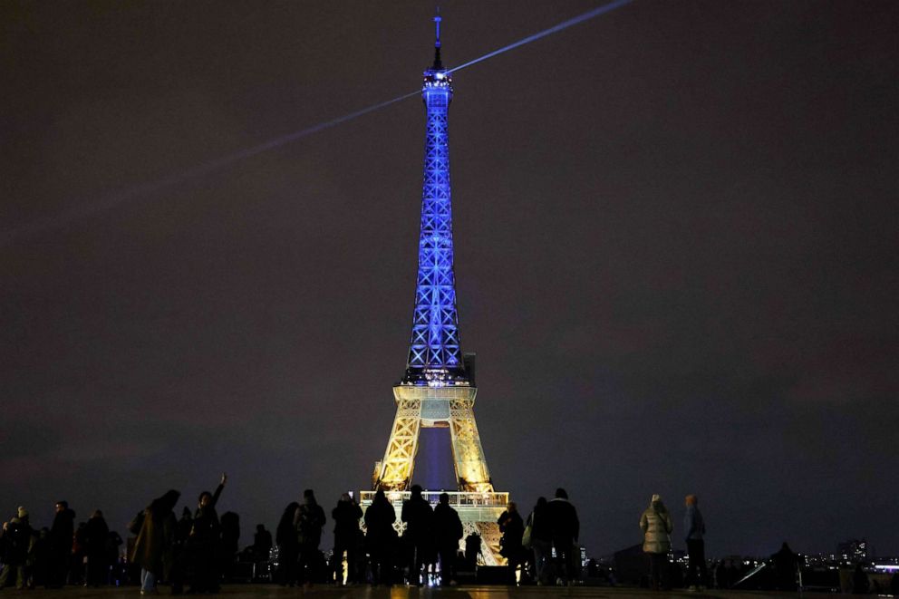 PHOTO: Bystanders watch the Eiffel Tower lit in the colors of the Ukrainian flag in a show of support to Ukraine, one year after Russia launched a military invasion on the country, in Paris on Feb. 23, 2023.