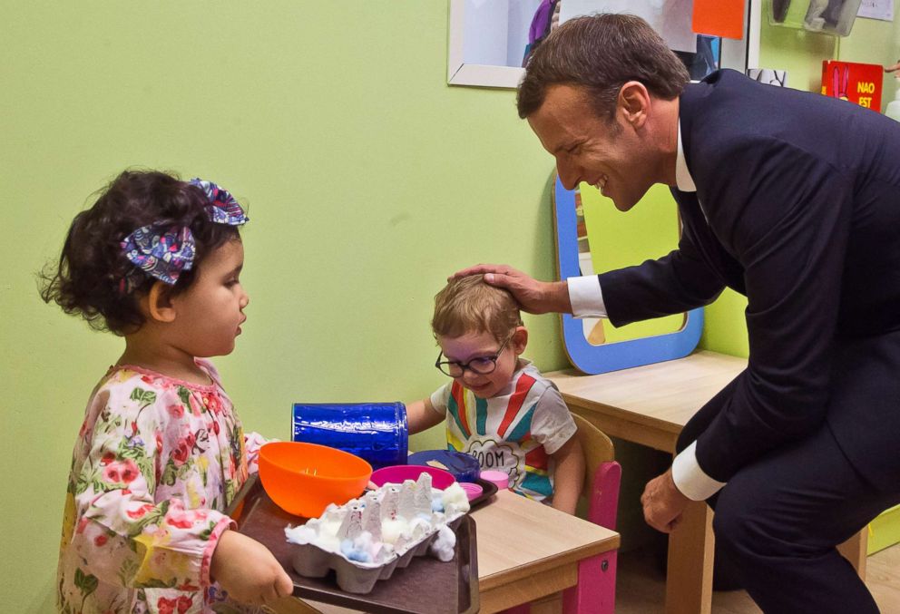   PHOTO: French President Emmanuel Macron speaks to children by visiting a daycare as part of a plan to fight poverty for children and youth in the country, in Gennevilliers, near Paris, on 17 October 2017. 